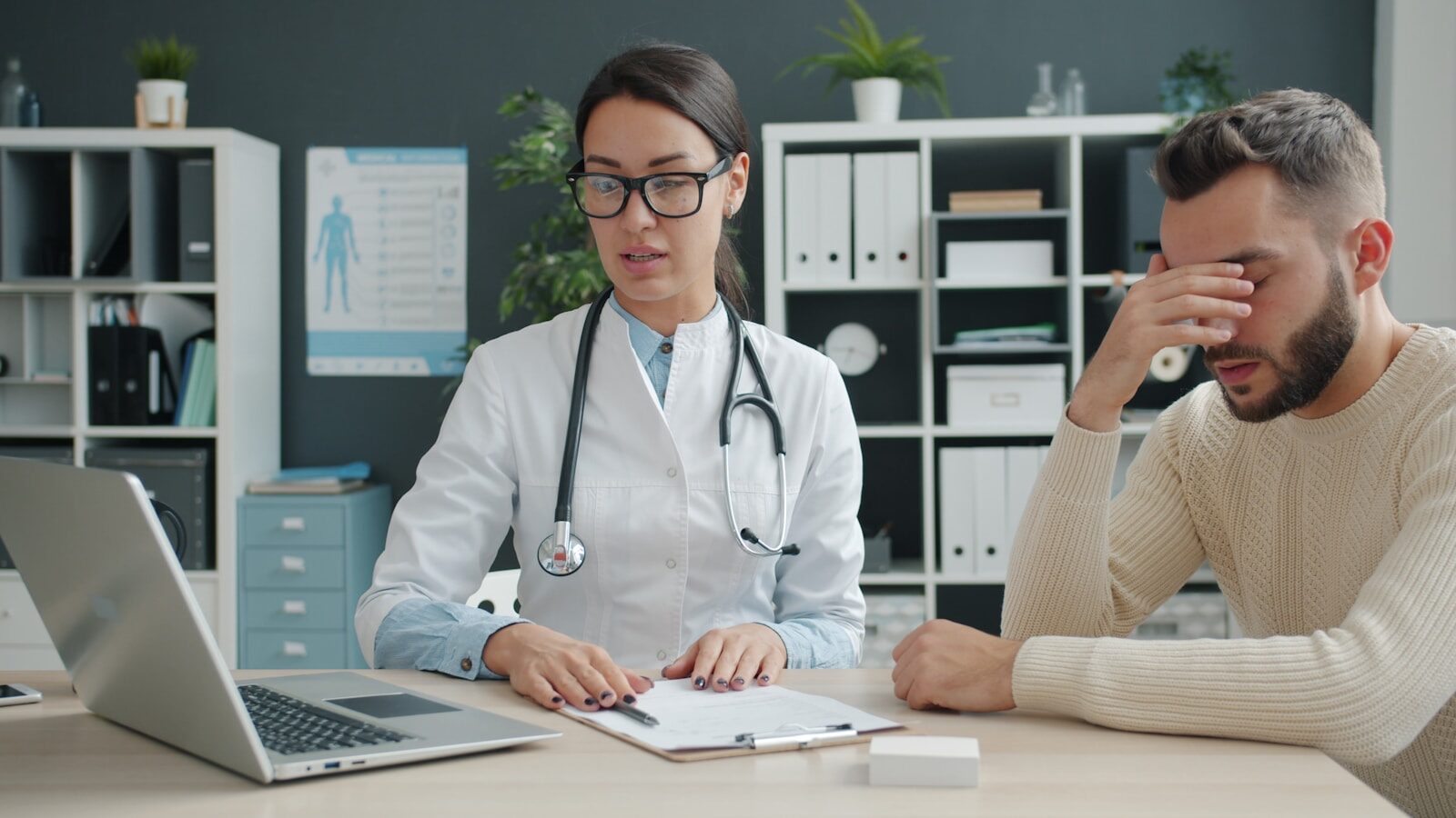 Doctor consults with a distressed male patient in office.